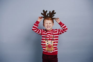 Playful boy with reindeer antlers at studio shot
