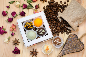 Delicious truffles in the box, a canvas bag with coffee beans, dry flowers, star anise located on wooden background