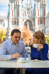 Couple of happy tourists drinking coffee on european city street in outdoors cafe, talking having fun laughing smiling happy summer holidays and dating concept in the city
