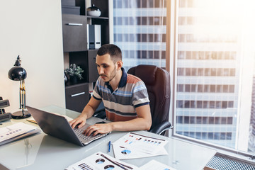 Businessman working on laptop sitting at desk in office