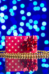 Gift in package and golden beads on a glass table with a beautiful blue bokeh - 184251592