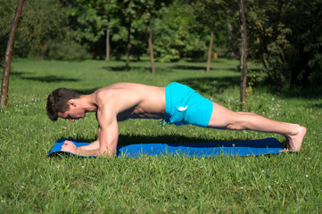 Fototapeta premium Sportsman do handstand on blue mat in park