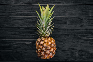 Pineapple on a wooden background. Top view. Free space for text.