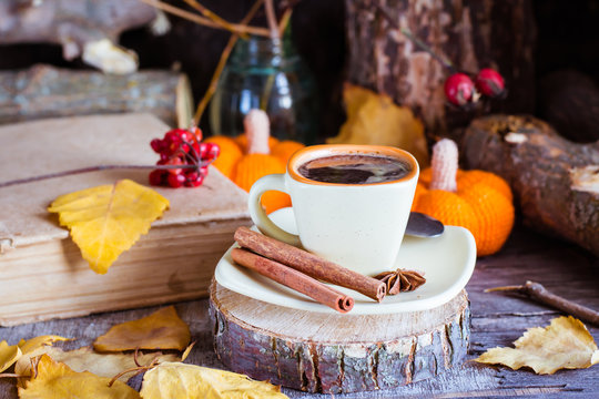 Autumn still life with coffee drink. A cup of black coffee and cinnamon on a cut of a tree.