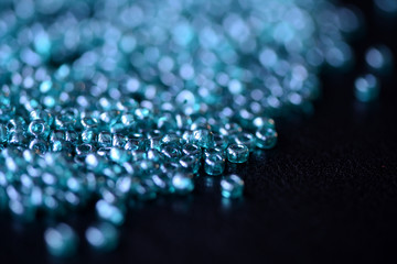 Scattered seed beads aquamarine color on a dark surface close up