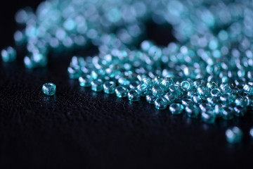 Scattered seed beads aquamarine color on a dark surface close up