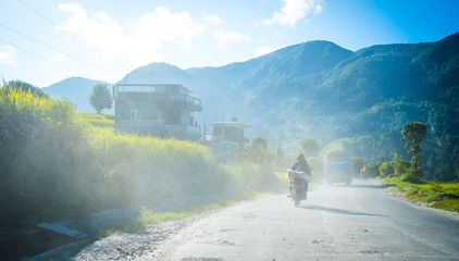 Motorcyclist and bus at sunset on the road in Annapurna mountain village, Nepal.