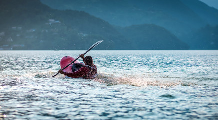 Kayaking with splashes on red kayak on lake, Pokhara, Nepal.