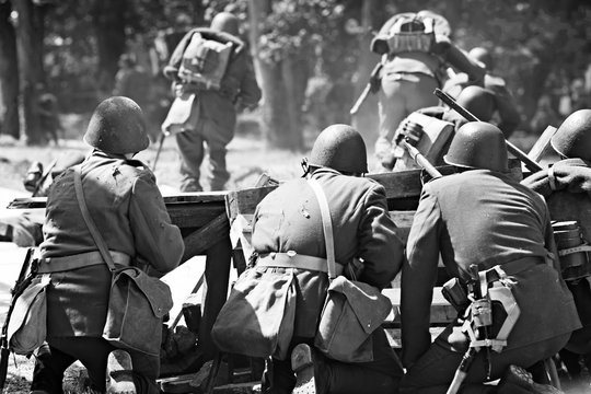 Czarno-białe ujęcie grupy żołnierzy w hełmach tłoczących się na barykadach podczas walki we Wrześniu 1939 roku, rekonstrukcja historyczna