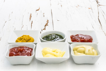 Classic set of sauces in square white sausers on surface with cracked paint