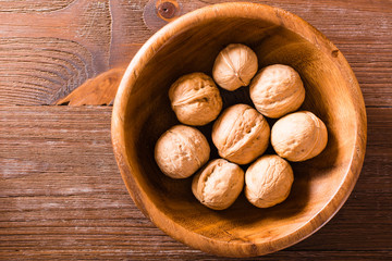 Plate with walnuts on a wooden table. Top view