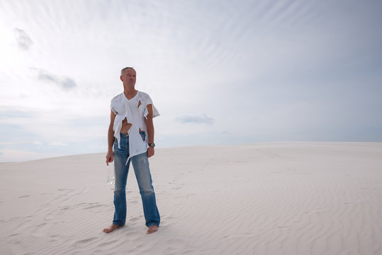 Exhausted man, lost in the desert, is standing on a sand dune