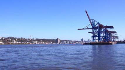 Fototapeta na wymiar HAMBURG, GERMANY - MARCH 8th, 2014: View on the Burchardkai of the Hamburg harbor. Container ship TABEA is unloaded and loaded during a clear blue sky day