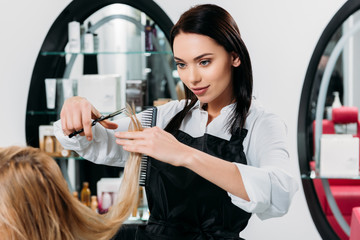 cropped image of attractive hairdresser trimming ends of hair