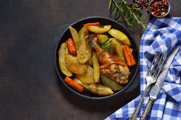 Homemade dinner. Chicken baked with potatoes, carrots with herbs on a dark background.