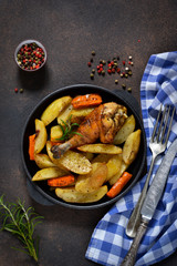 Homemade dinner. Chicken baked with potatoes, carrots with herbs on a dark background.