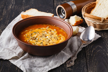 Vegaterian hot pumpkin soup serving in bowl on rustic table