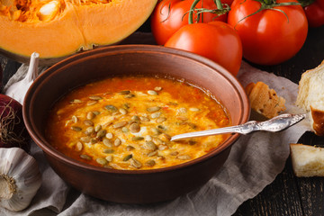 Homemade pumpkin soup in brown bowl on rustic table