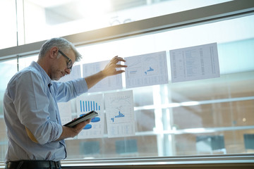 Businessman analyzing results charts hanged on office window