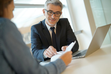 Woman in banker's office signing financial loan for project