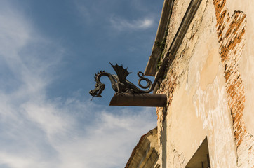 Fototapeta na wymiar Decorative iron dragon under the roof, decoration element on the facade of the castle