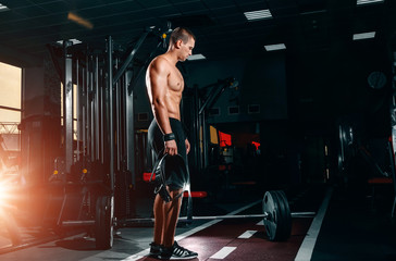 Fototapeta na wymiar Muscular athletic bodybuilder fitness model posing after exercises in gym