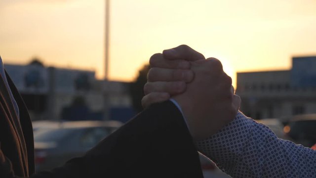 Friendly handshake of two unrecognizable businessmen in urban environment. Business handshake outdoor. Shaking of male arms outside. Colleagues shake hands in the city background. Close up Slow motion