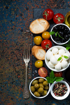 mozzarella, ingredients for the salad and bread and dark background, top view