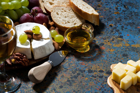 snacks, glass of wine and Camembert cheese on a dark background