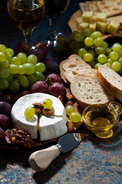 snacks, fruit and Camembert cheese on a dark background, vertical closeup