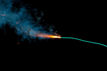 Burning fuse with sparks and blue smoke isolated on black background