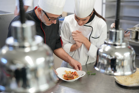 Professional cook chefs in kitchen improving dish composition
