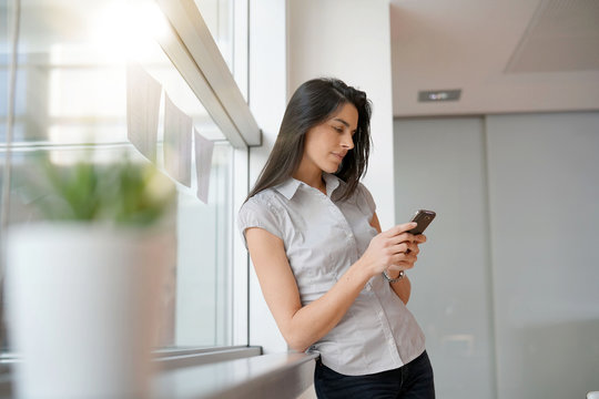 Businesswoman in office relaxing, using smartphone