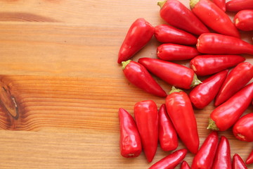 The multitude of red hot chilli peppers on the wooden table with copy space with a blurred background. Free place for text.