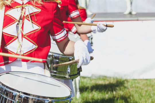 girl in red coat playing marching drum