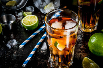 Cuba Libre, long island or iced tea cocktail with strong alcohol, cola, lime and ice, two glass, dark background copy space