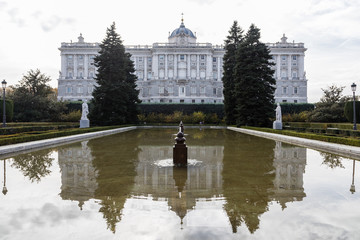 Fototapeta na wymiar Facade of the Royal Palace of Madrid with tourists passing by its side