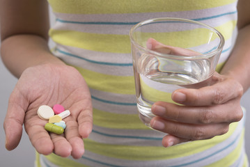 women hand holding glass of water are taking medicine for healthy.