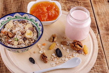 Healthy breakfast. Ceramic bowl with oat flakes, dried fruits, nuts on wood background