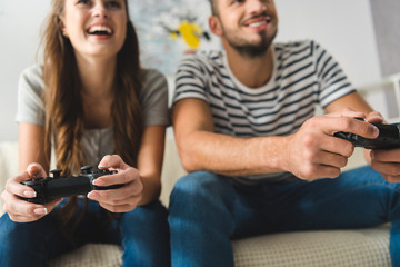 close-up shot of young couple playing games with gamepads at home