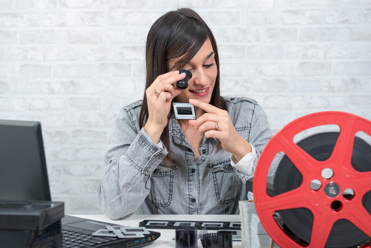 young  woman looking at film slide with magnifying glass