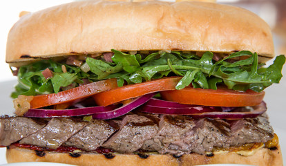Delicious big steak sandwich. Close up. Juicy meats and vegetables