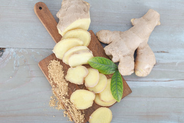 Fresh ginger root and ginger power on chopping board with sliced ginger
