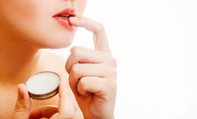 girl and balm, close-up girl is applying balm to the lips on white background