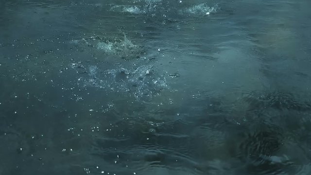 slow motion of heavy rain water drops or foutain on surface street, seamless loop ready