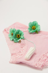 Obraz na płótnie Canvas Hygienic tampon and sanitary napkin for every day with panties with green flowers on a white background