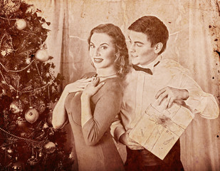 Christmas nostalgy couple on party near Xmas tree take gift box. Happy family on holiday. Vintage...