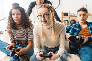 group of multiethnic teens playing video game at home