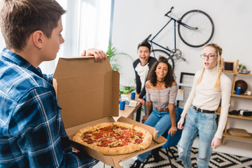 teen boy showing friends smelling pizza