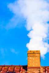 Modern house roof with chimney smoke, air pollution by co2 emission, reason of smog in winter